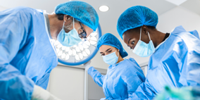 Group of clinicians in scrubs and surgical caps in a cleanroom environment collaborating on electrophysiology catheter design, testing and quality review.