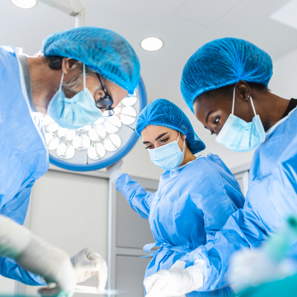 Group of clinicians in scrubs and surgical caps in a cleanroom environment collaborating on electrophysiology catheter design, testing and quality review.