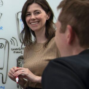 Phillips Medisize employees working on product design as part of the research and development process. They are working on a whiteboard with a number of Phillips Medisize devices drawn on the board including the Aria Smart Autoinjector and the Mini Tablet Dispenser.