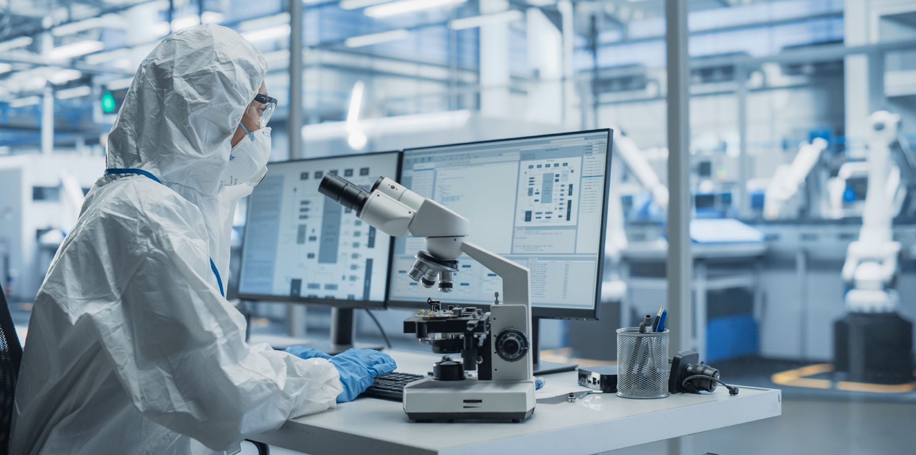 Medical device manufacturing cleanroom: engineer using ai and data analytics while inspecting a microchip. Scientist developing advanced electronics component.
