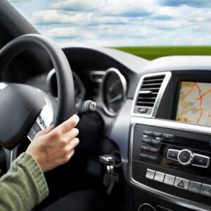 An image of a car steering wheel and the front console of a car, showing the satellite navigation on the screen.