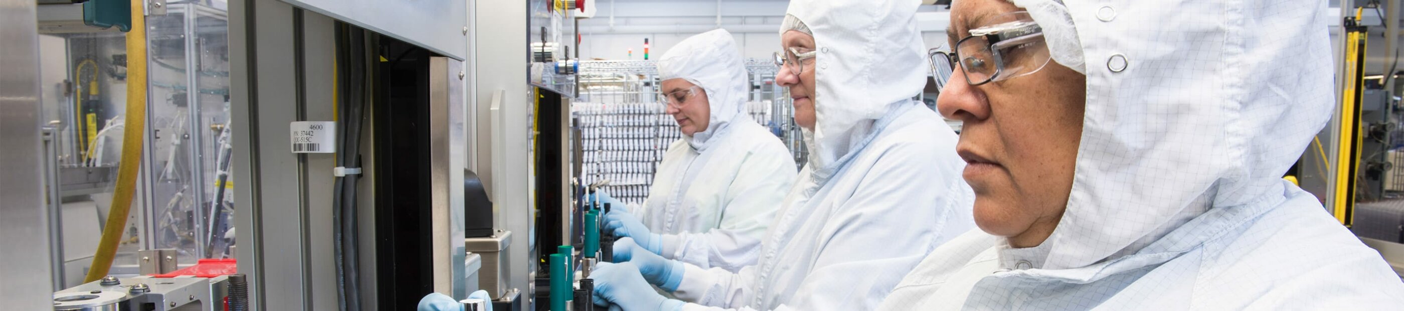 women in white hazmat suit working on machines