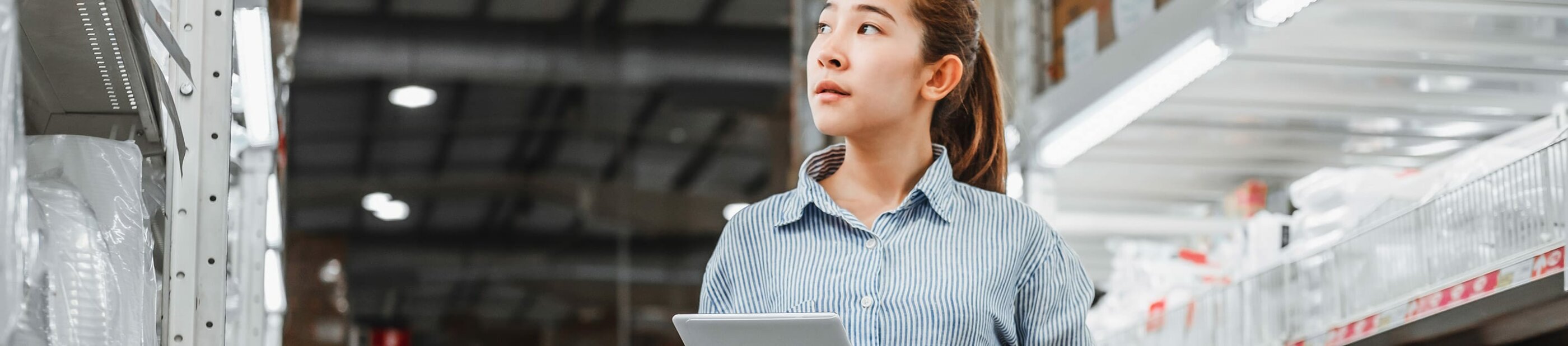 woman holding tablet looking at racks in warehouse