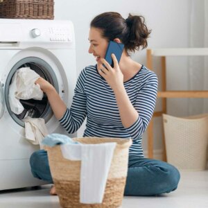 Close-up partial view of woman using washing machine at home depecting consumer product manufacturing