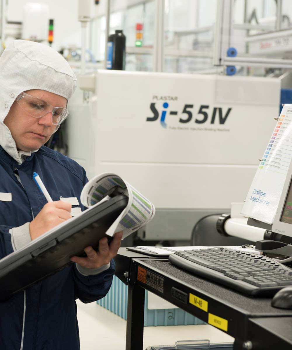 woman taking notes on clipbard in manufacturing facility