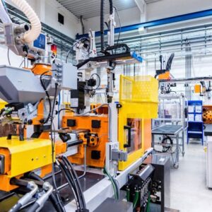 An image of injection molding machines in a large well-lit factory ready for production