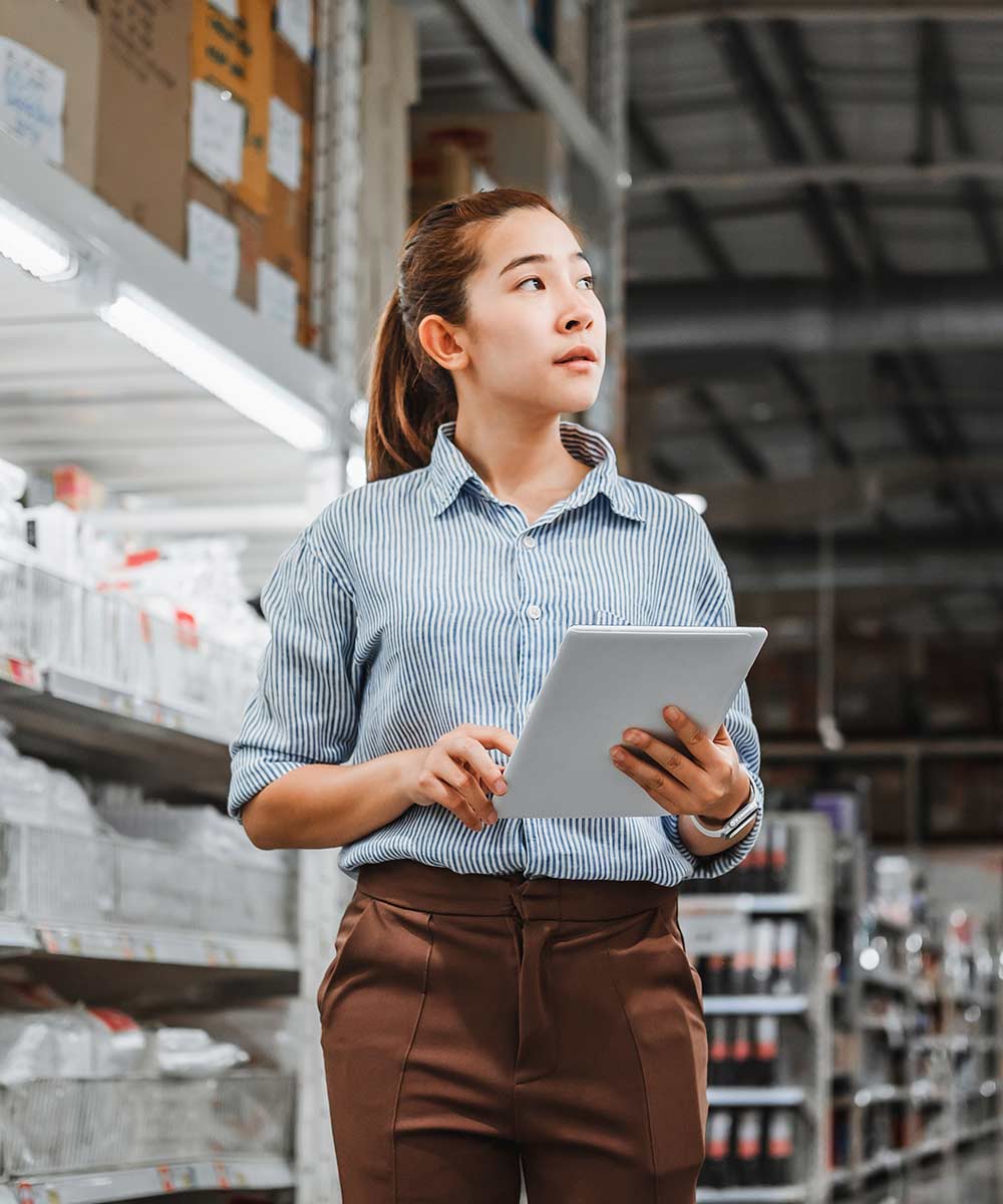 woman holding tablet looking at racks in warehouse