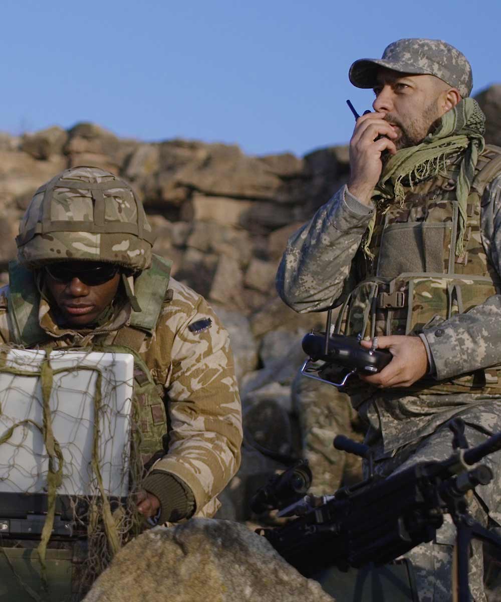 two man in army uniforms out on duty in a field