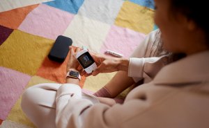 A close-up image of a smart phone monitoring a CGM device on the individual's arm